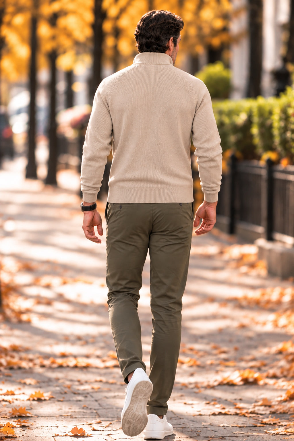 Man walking in a beige half-zip knit sweater and olive chinos – back view