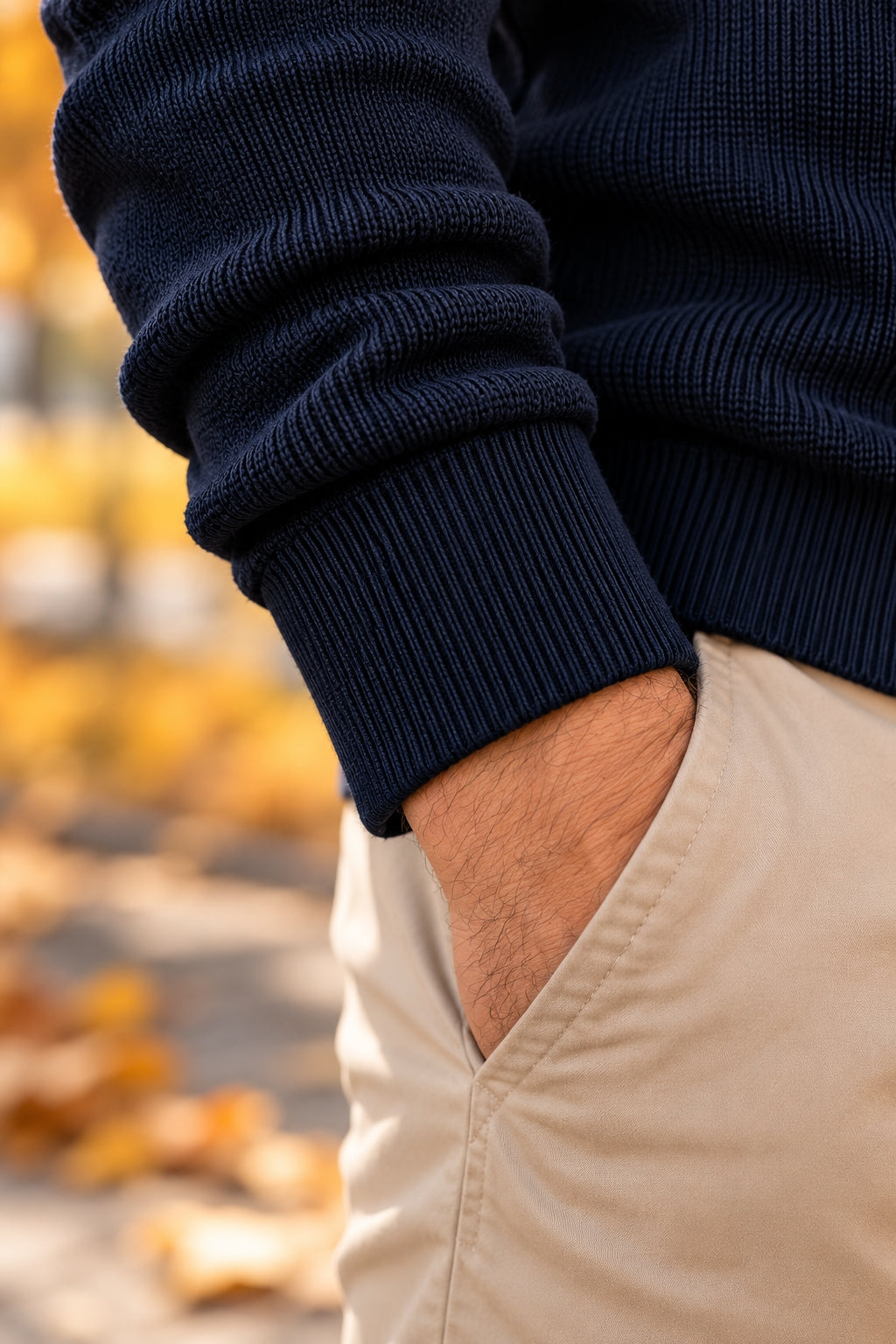 Close-up of the navy sweater's ribbed cuff with a hand in a chino pocket